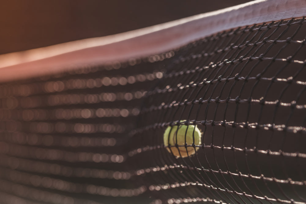 Tennis ball hit into the middle of the net